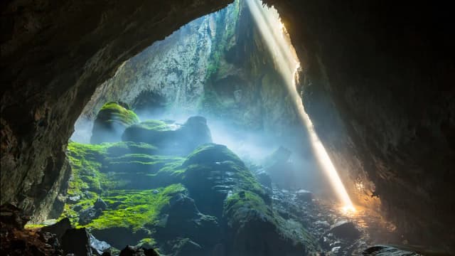 Explorers venture through Son Doong Cave, the largest cave in the world, navigating colossal stalagmites and an underground rainforest illuminated by sunlight streaming through ceiling openings
