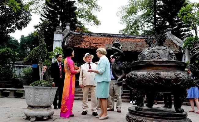 A group of foreign tourists dressed in culturally appropriate clothing explores a Vietnamese temple, engaging with the intricate architecture and serene surroundings