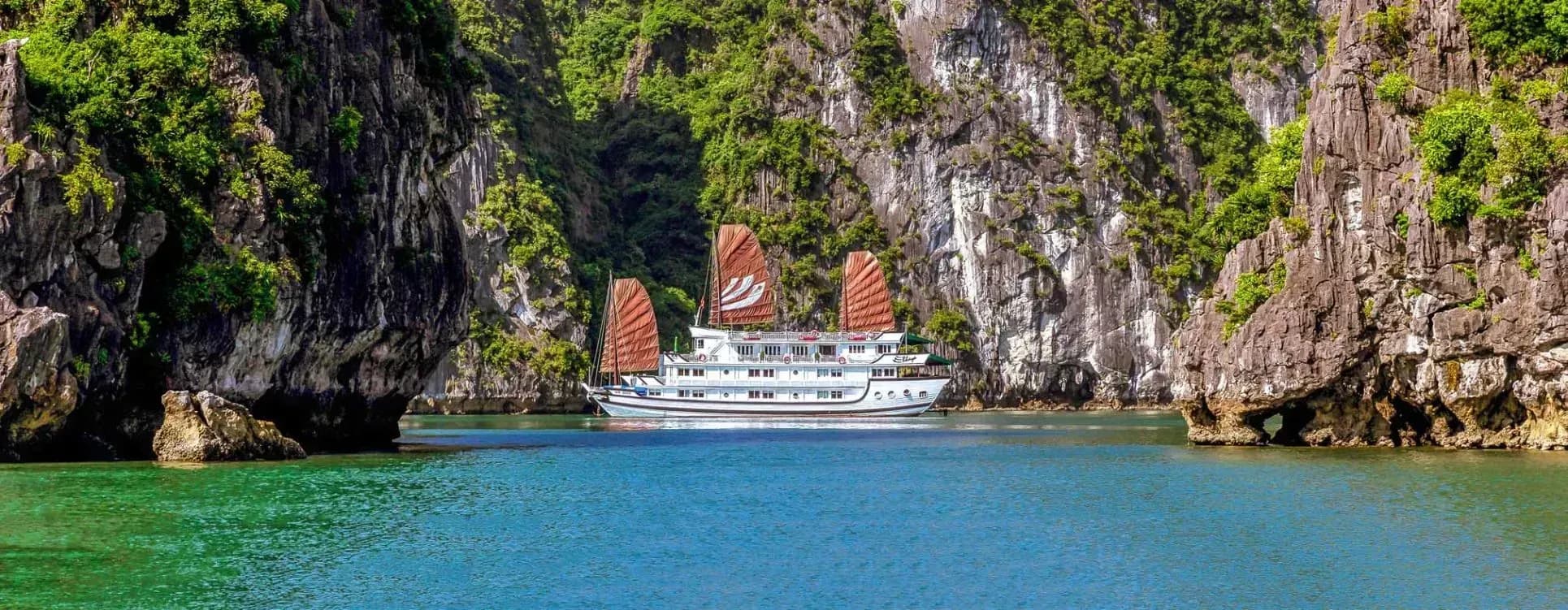 Bhaya 크루즈는 Ha Long Bay의 mossy 석회암 절벽 사이 이동.