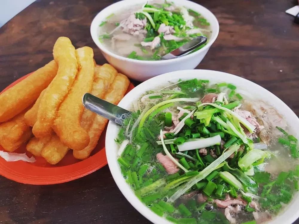 Delicious beef pho with crispy dough sticks, creating a delightful and satisfying meal.