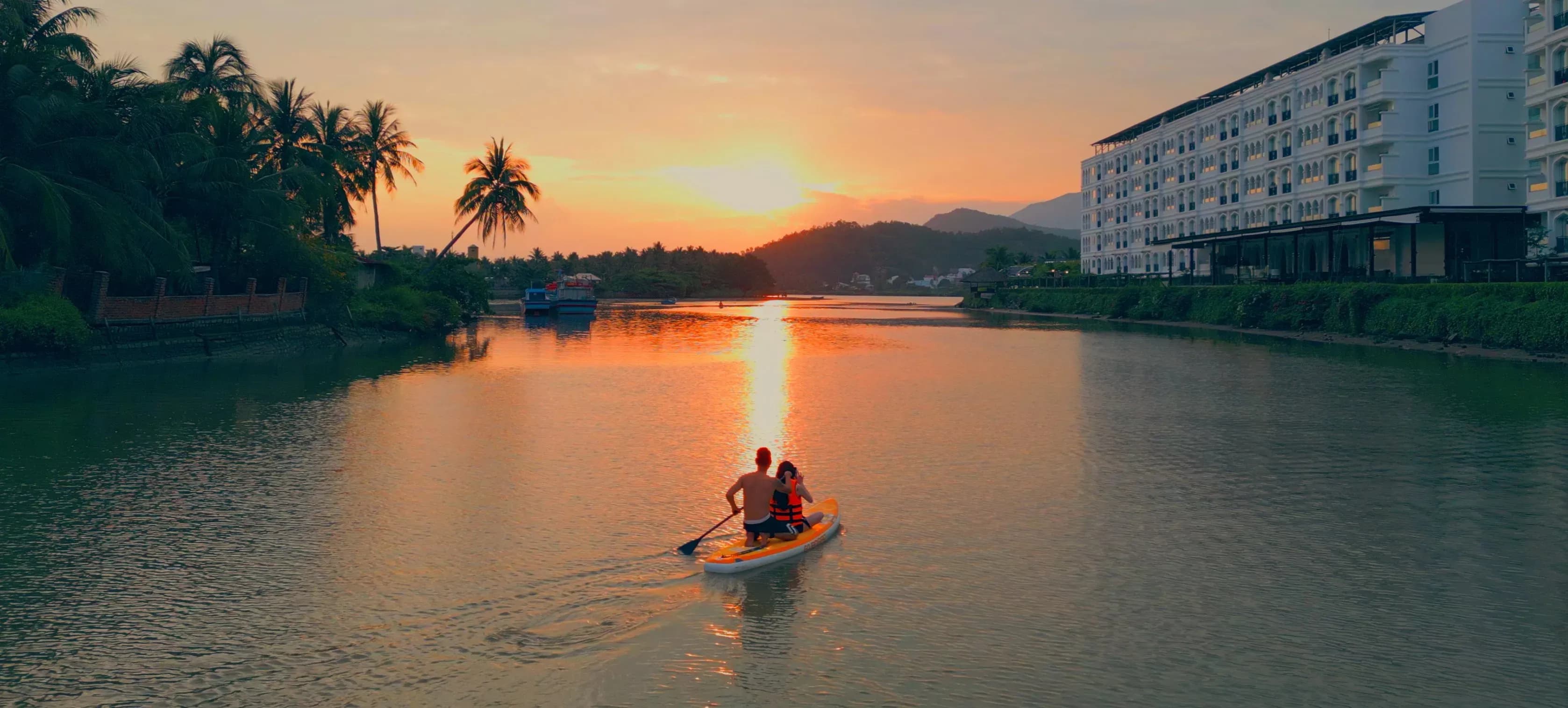 Sunset over the river with two tourists paddling, creating a serene scene at Champa Island.